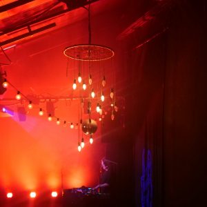 Photo d'un grand lustre dans une ambiance tamisée orange, au Club de La Lune des Pirates.