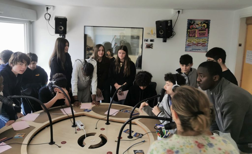 Photo montrant un groupe d'une quinzaine d'adolescent·es dans un studio de radio.